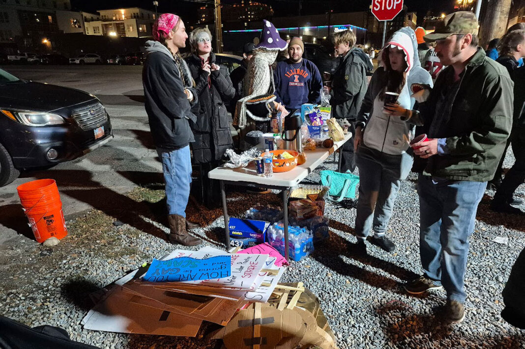 Protest signs laying on ground next to people serving food