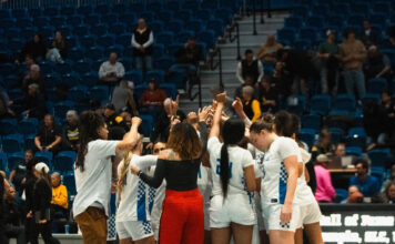 SLCC women’s basketball head coach inspires players beyond the court Women's basketball coaches and players huddling in a circle on the court