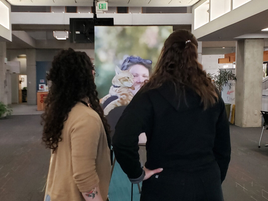 Two people looking at a portrait on canvas