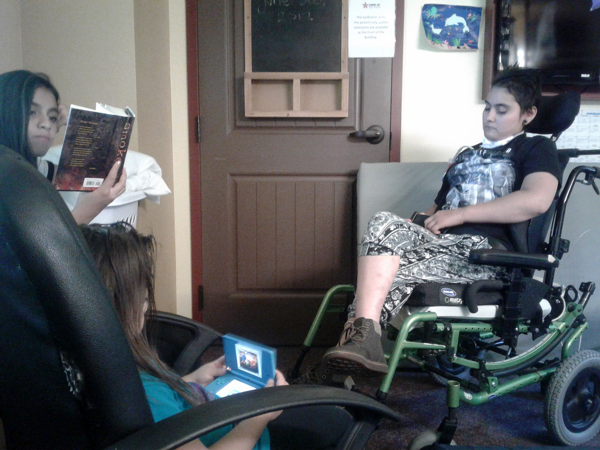 Sisters spending time with Delmy, who is sitting in a transport chair