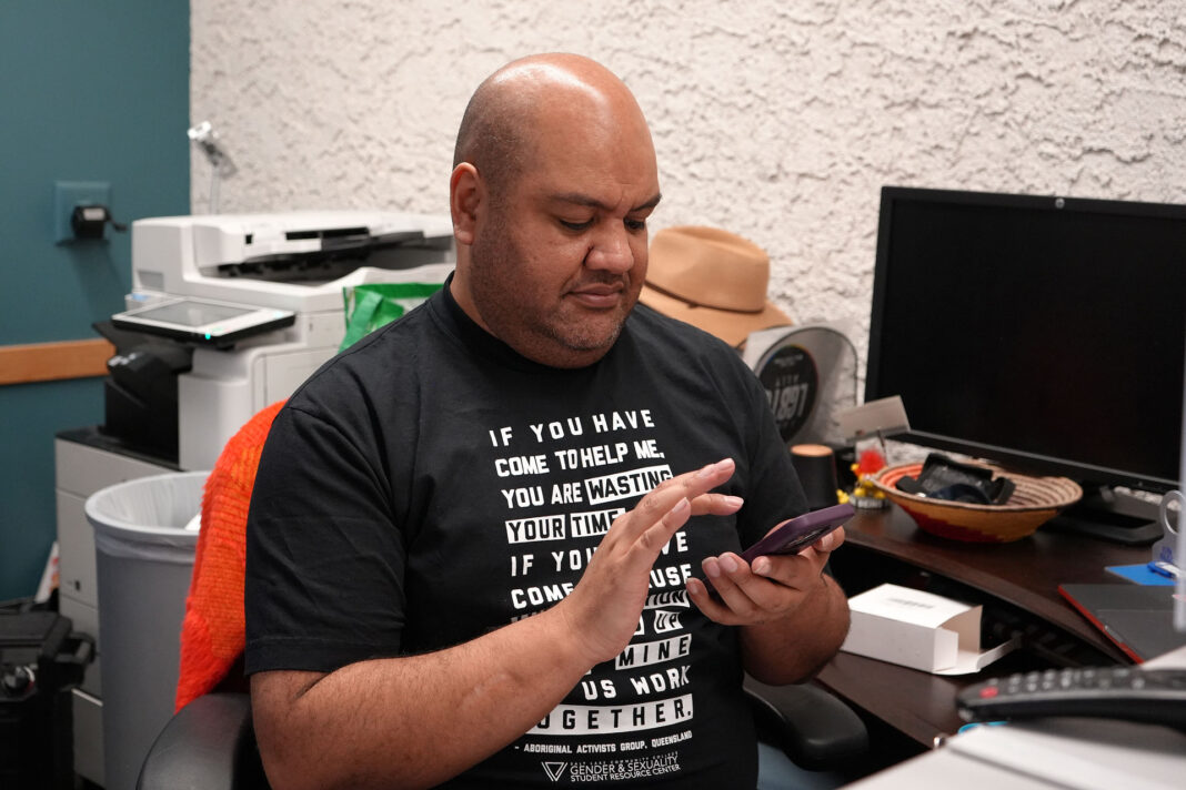 Leka using a mobile phone at their desk