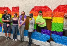 Students say closure of Gender and Sexuality Student Resource Center cuts off vital support Several people standing together by rainbow-colored SLCC letters