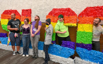 Students say closure of Gender and Sexuality Student Resource Center cuts off vital support Several people standing together by rainbow-colored SLCC letters