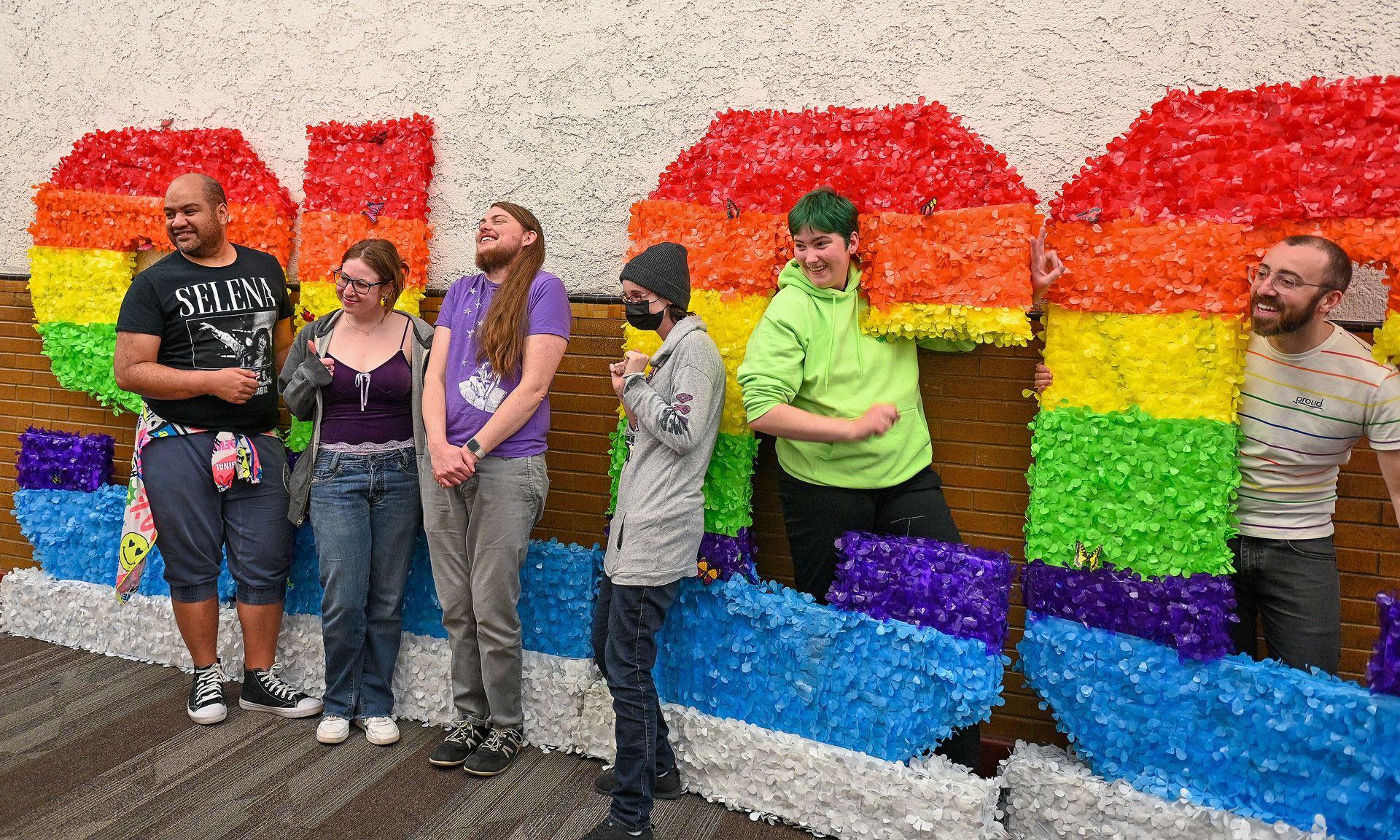 Several people standing together by rainbow-colored SLCC letters