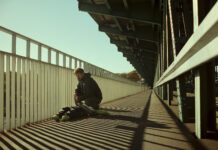 Sundance 2026: A father’s desperate search for his son in ‘Closure’ Daniel kneeling down near a weighted body dummy on a bridge