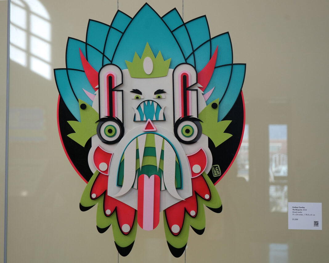 Multicolored mask made from mixed media being displayed on an LED wall