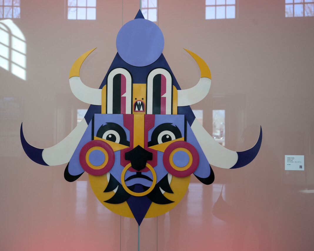 Multicolored mask made from mixed media being displayed on an LED wall