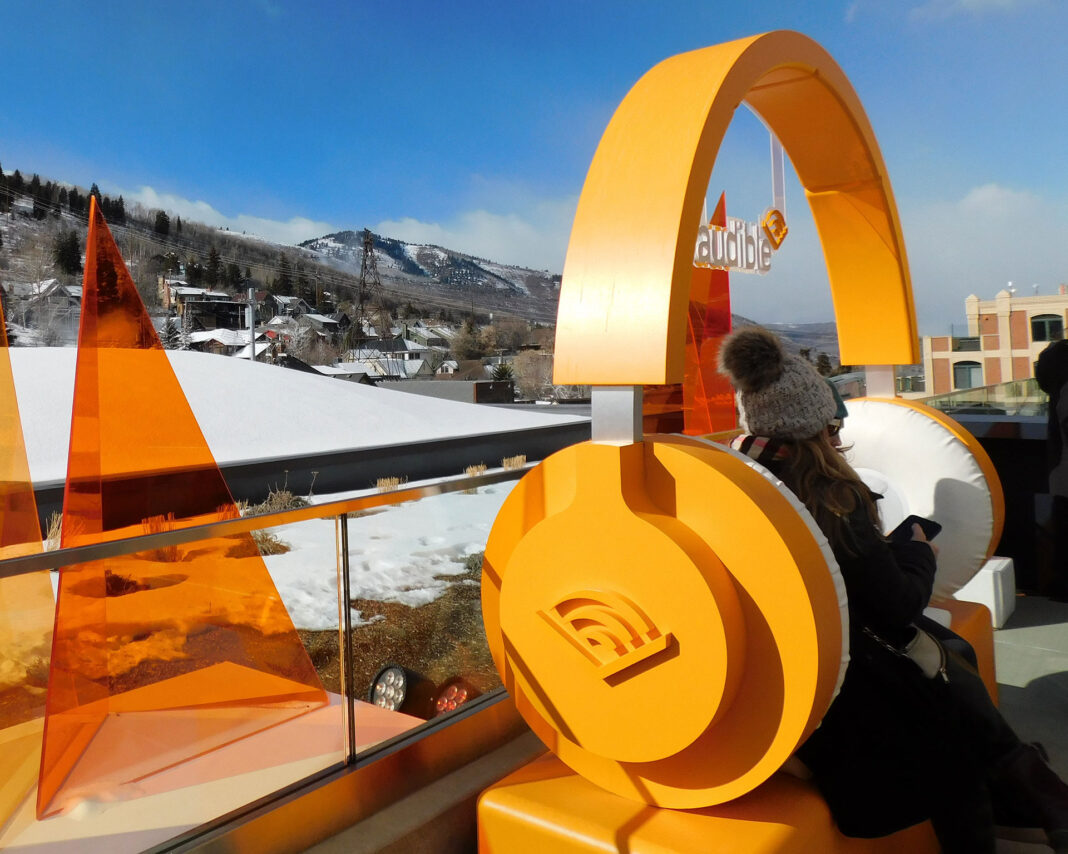Person sitting on a lounge underneath giant orange headphones