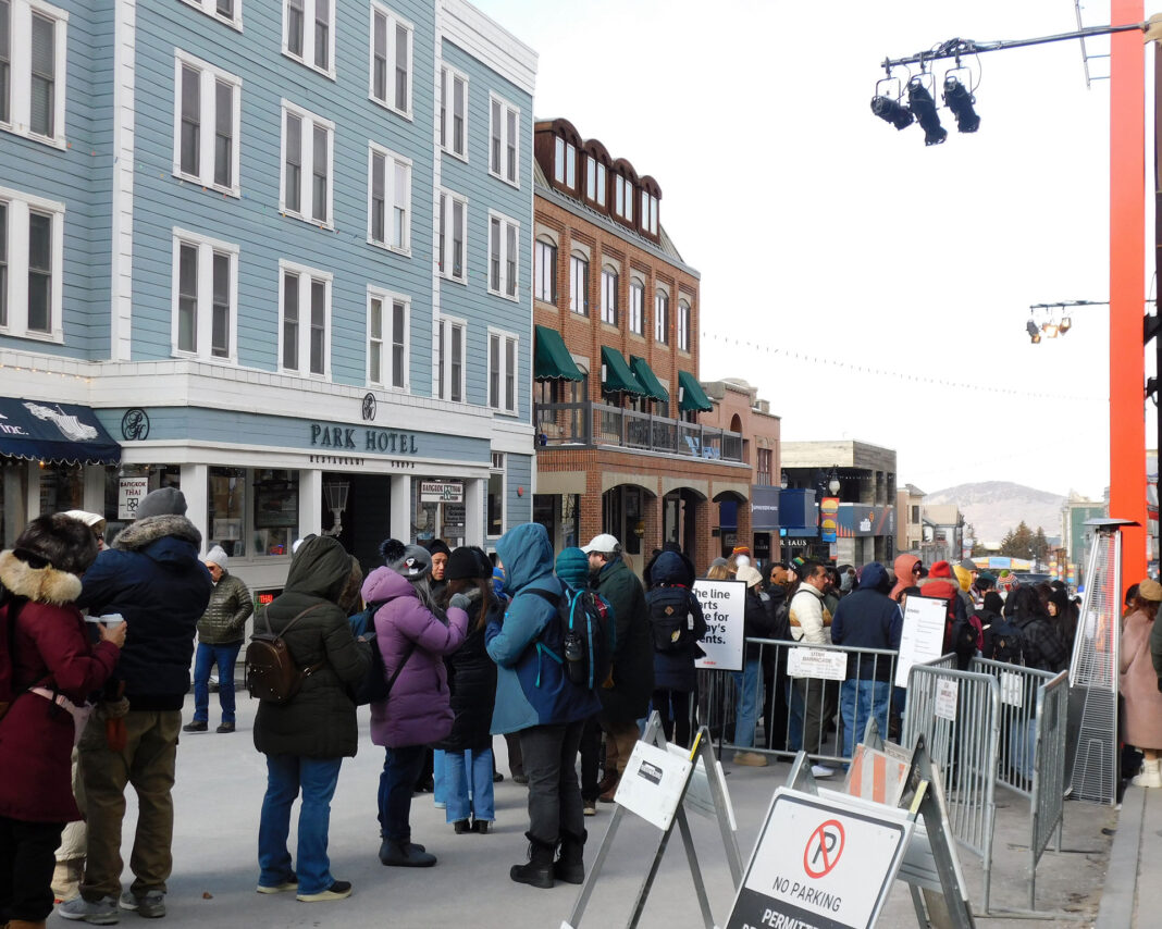 People standing and waiting in line outside on a city street