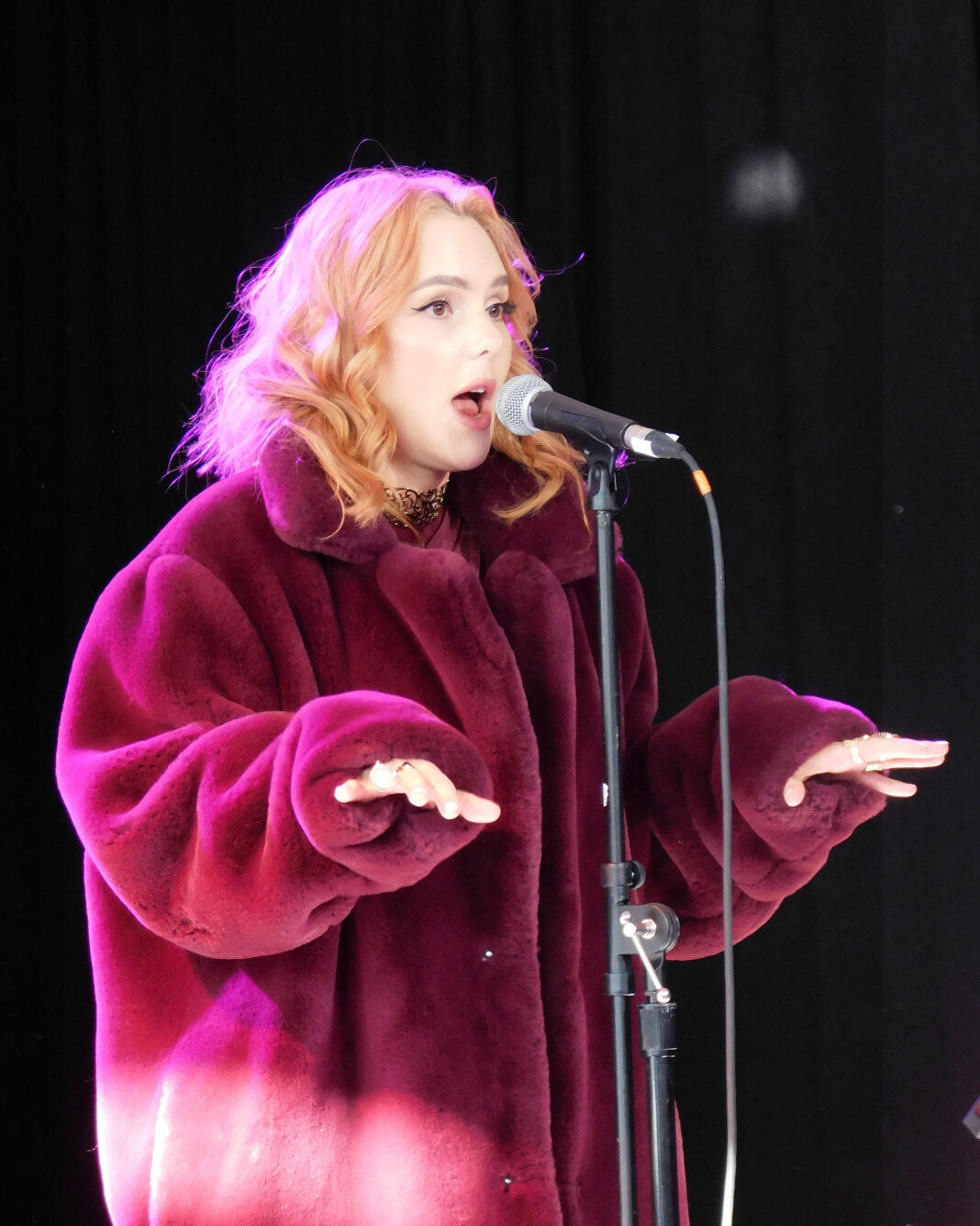 Nathalia singing and gesturing during a performance