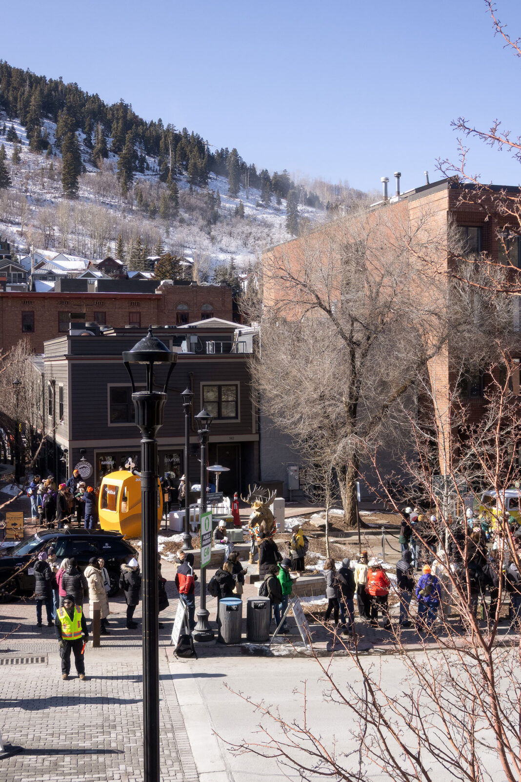 Portrait photo of crowd on the sidewalk and a background of mountain and buildings