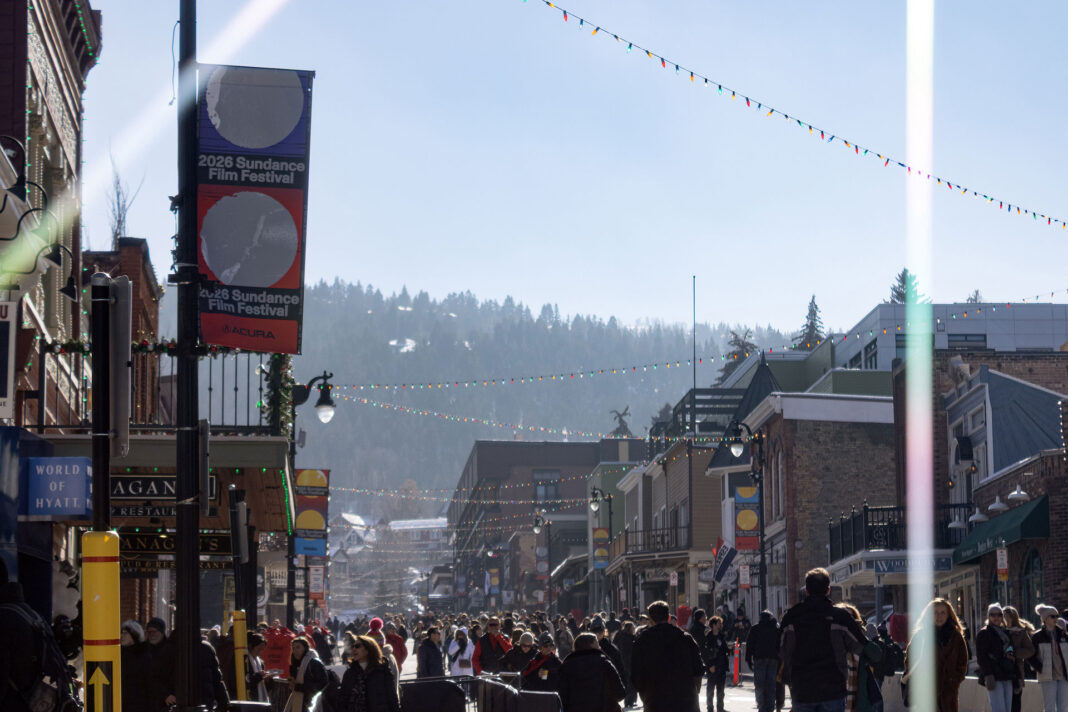 Landscape photo of a crowd and a Sundance Film Festival banner. Light streaks on purpose