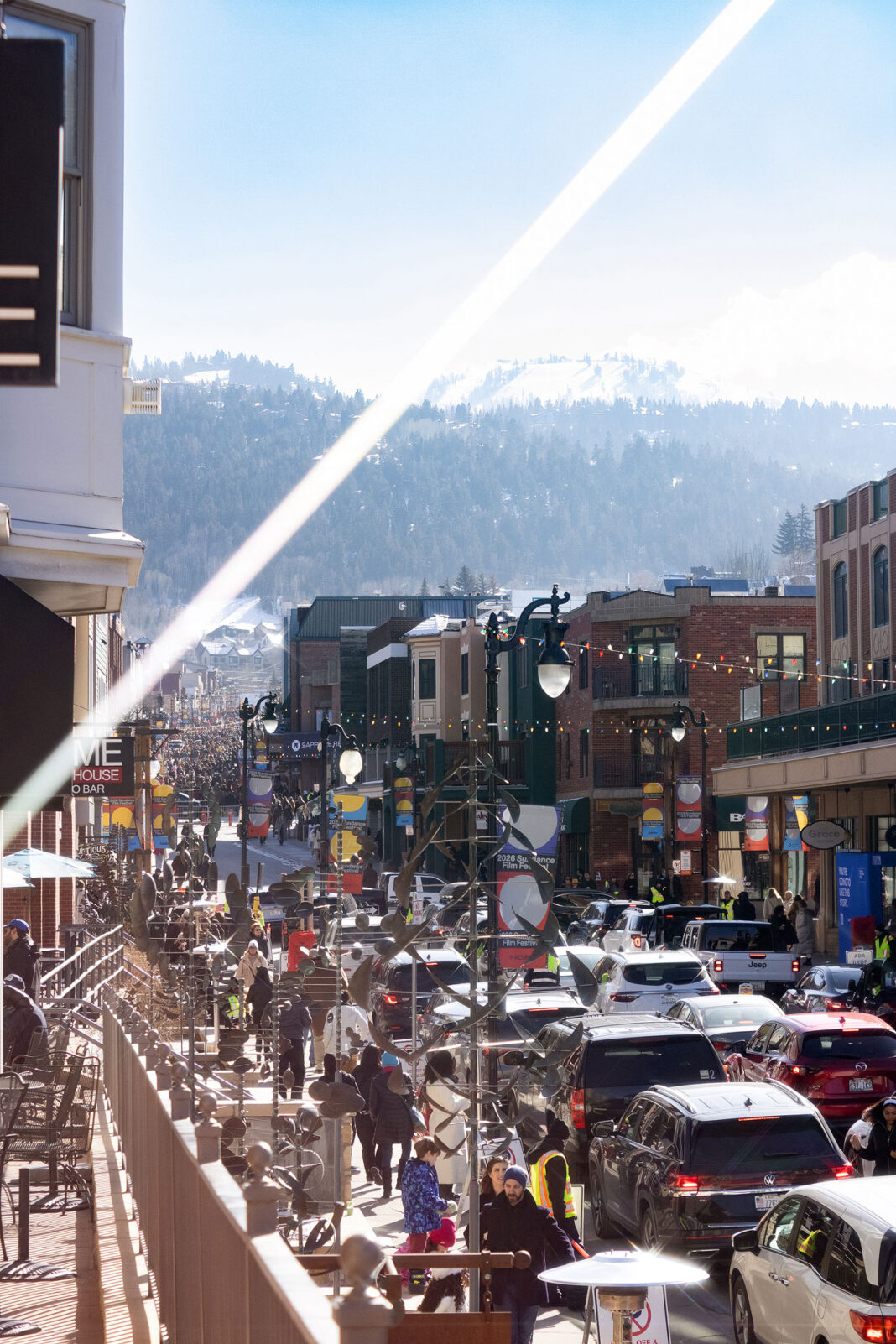 Portrait photo of Sundance Film Festival traffic with buildings, lights, cars, people, and mountain in frame. Light streaks are on purpose