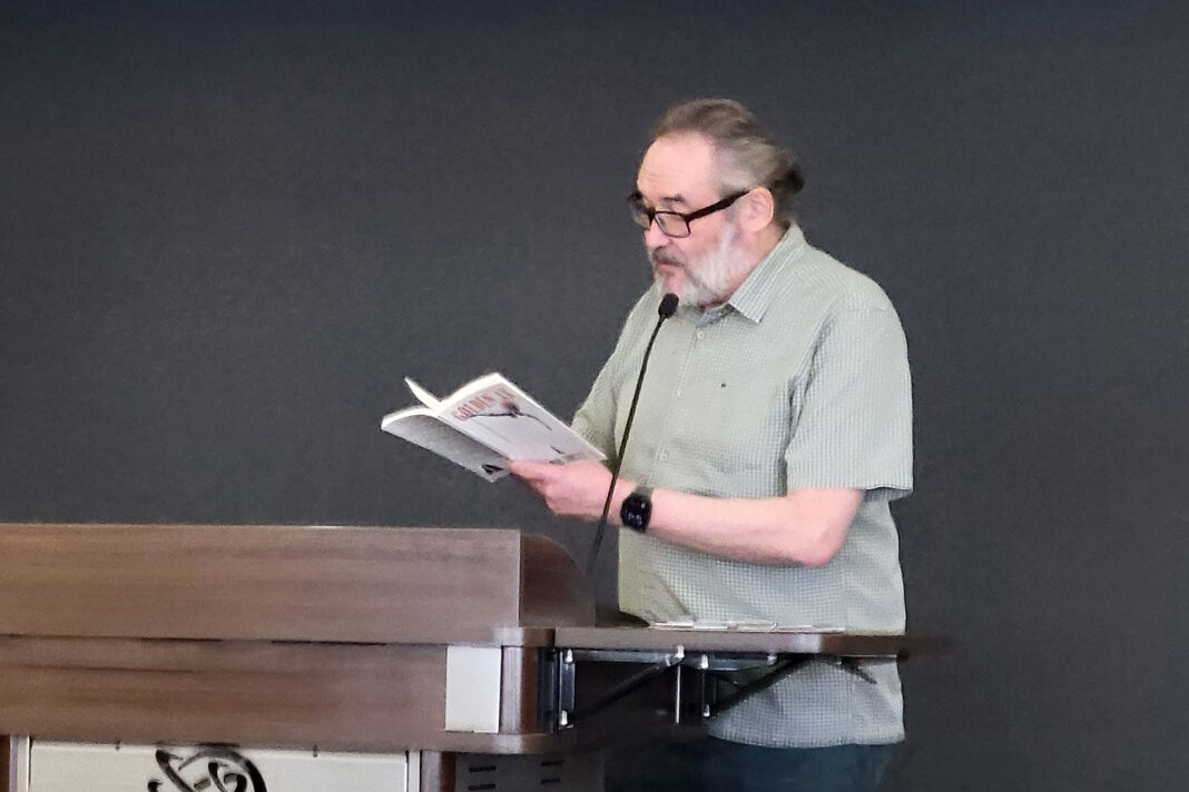 Clint Gardner standing at a lectern while reading