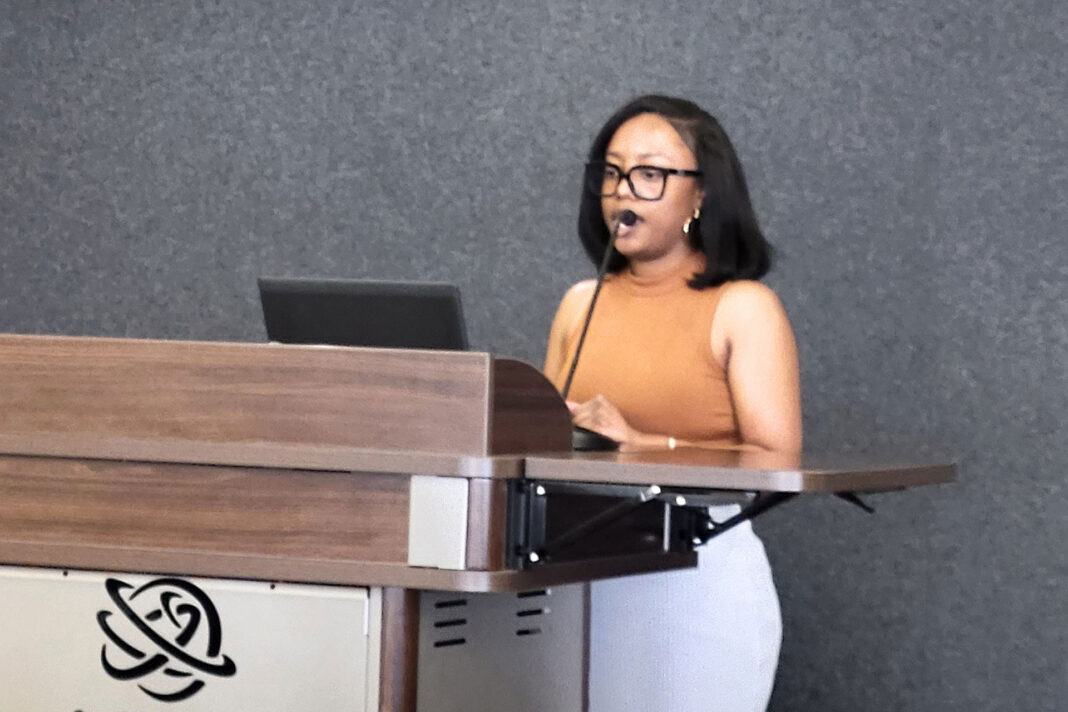 Shari-Fa Harrigan standing at a lectern while reading