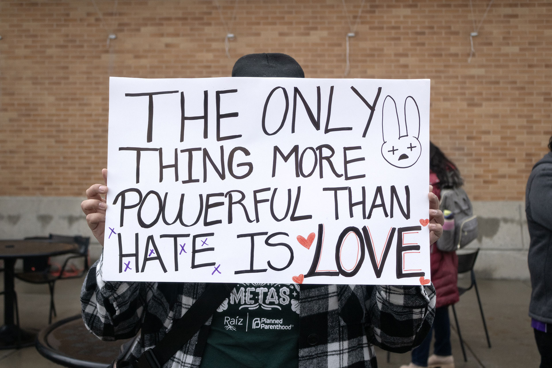 Landscape photo of a SLCC protester hold their hand made sign in front of their face