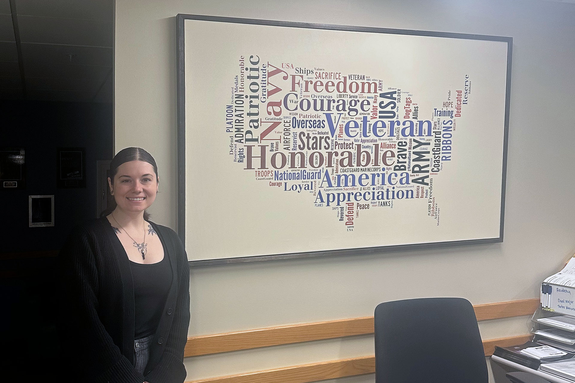 Ryan standing next to framed art of a word cloud in the shape of the United States