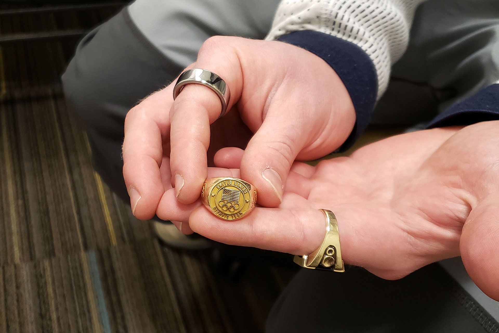 Landscape photo of Austin Kleba's hands displaying his Olympic gold ring