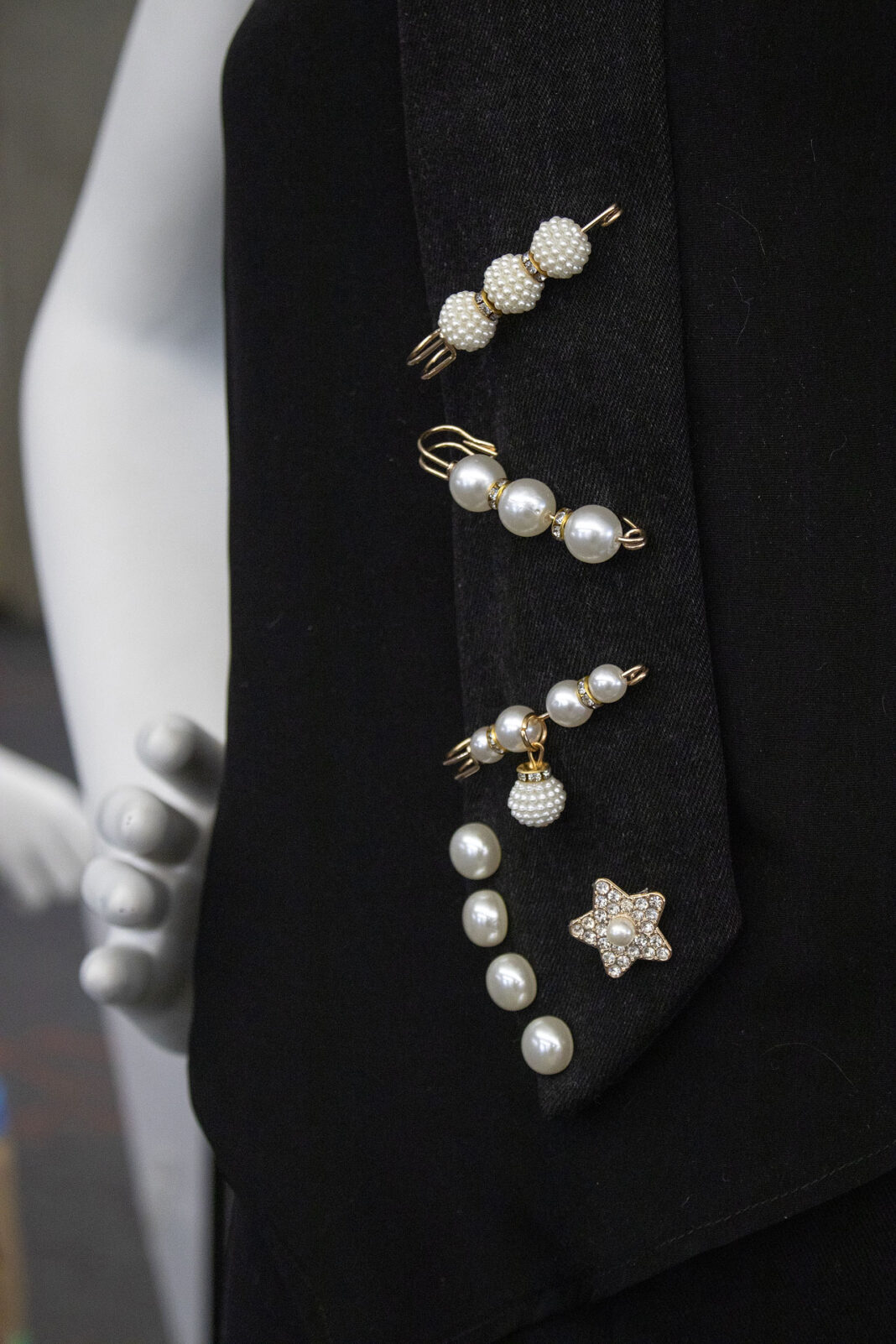 Close up of decorative pins and beads on a black sash