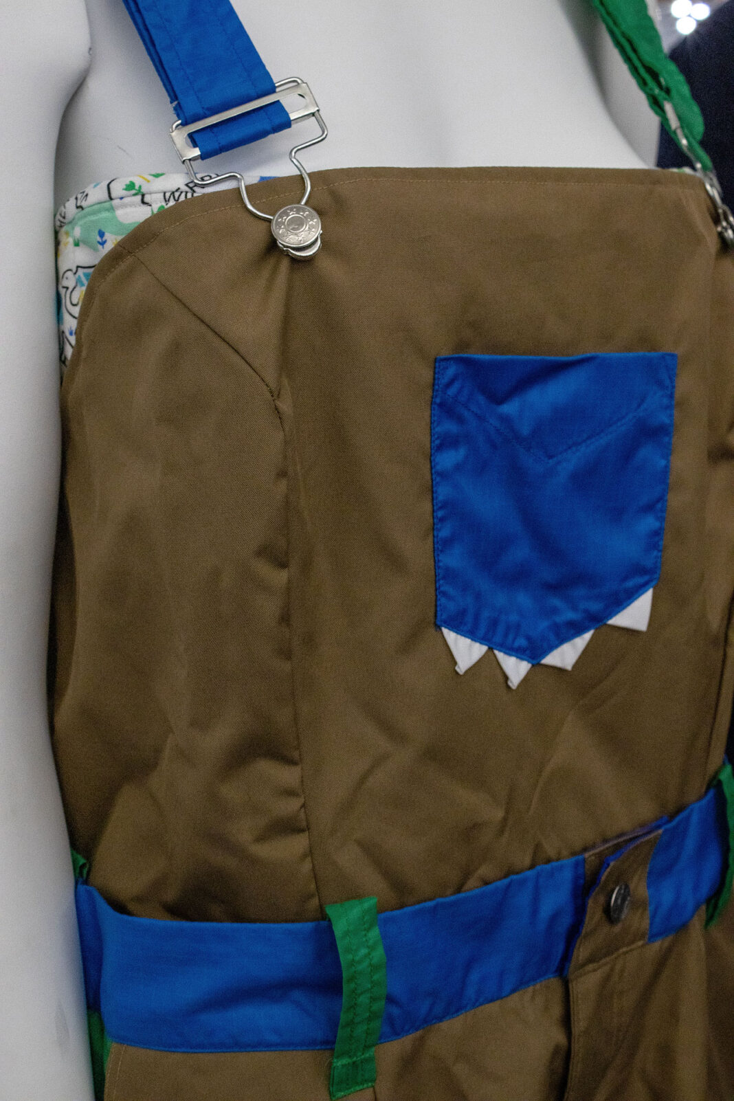 Close up of blue pocket, belt and suspenders on brown overalls