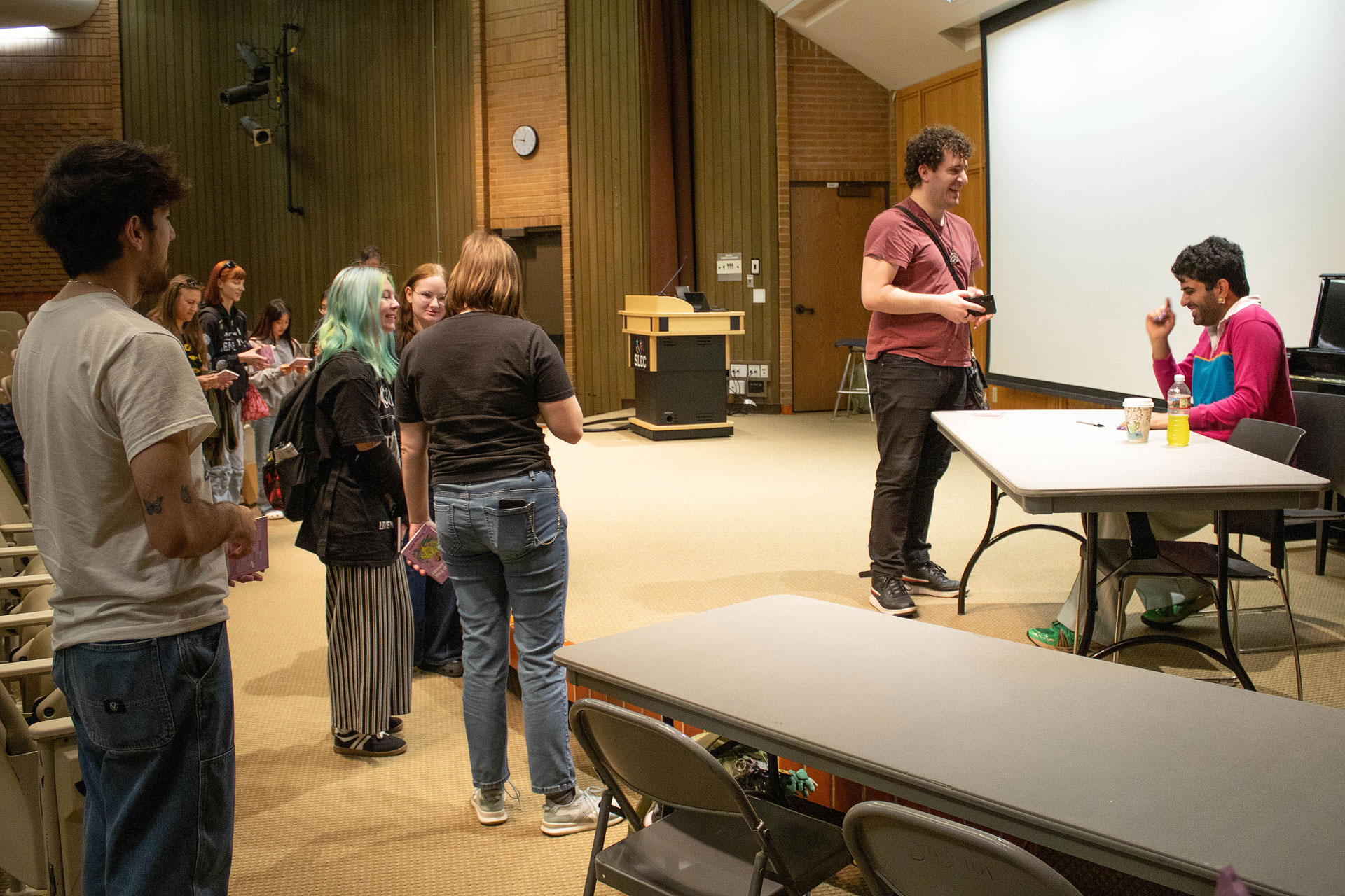 People standing and waiting to meet with Alok, who is seated behind a table