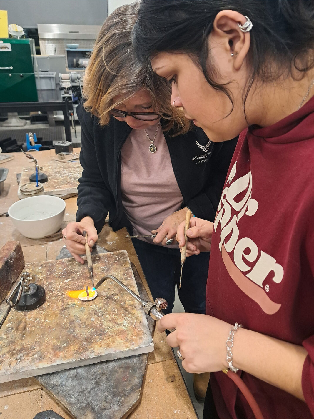 Student using a torch as instructor solders