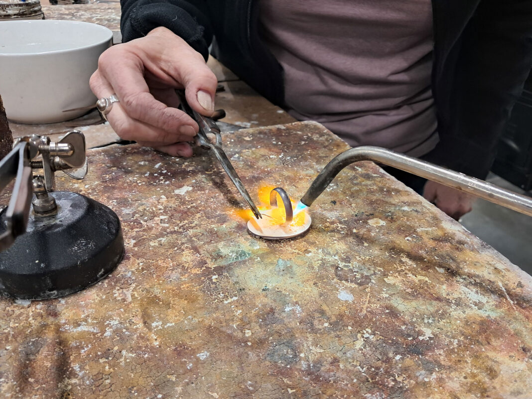 Student using a torch as instructor solders
