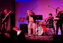 SLCC students showcase growth at mid-spring band concert Four students performing on stage under red and blue lights