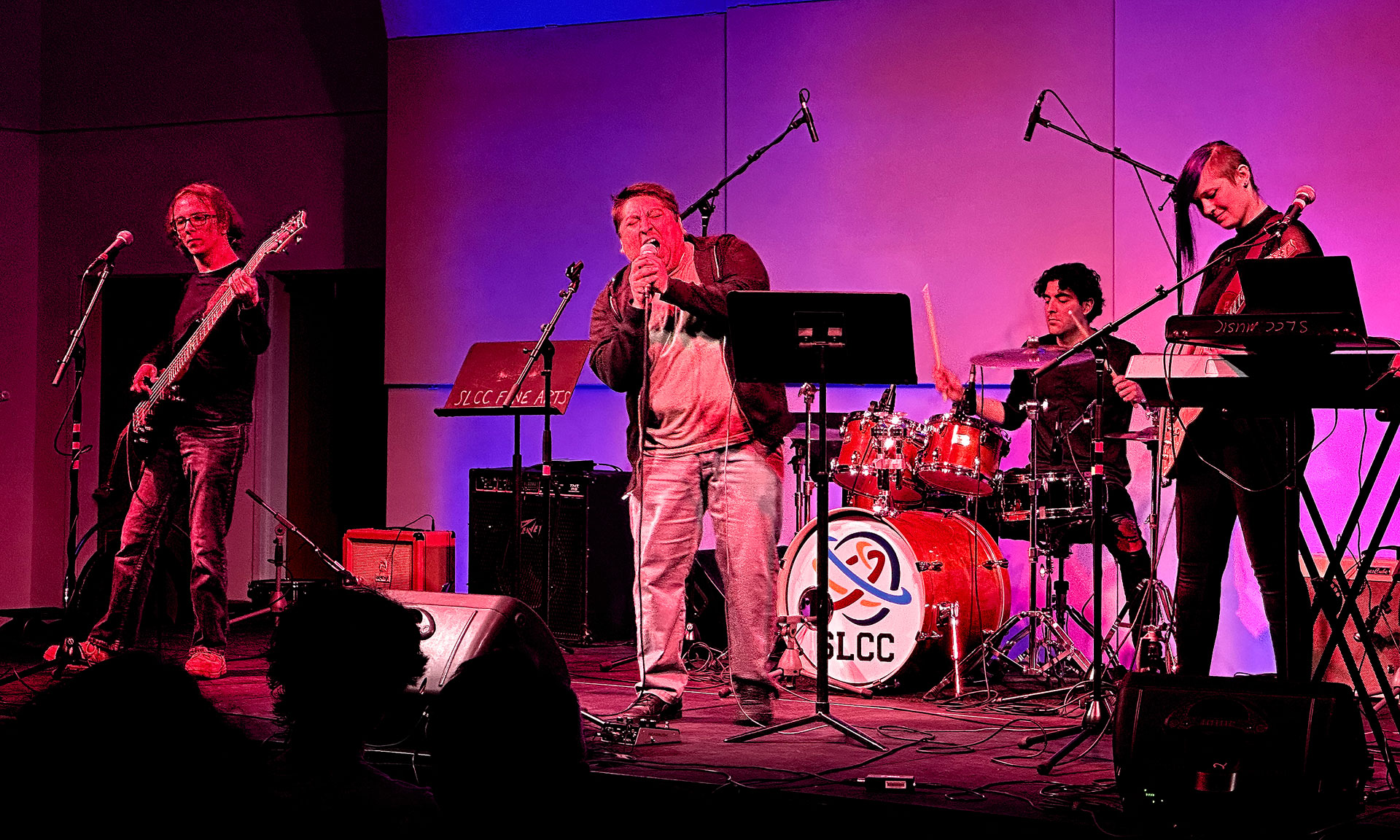 Four students performing on stage under red and blue lights
