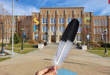 SLCC’s Native students describe challenges in finding community Person holding a feather in front of a brick building