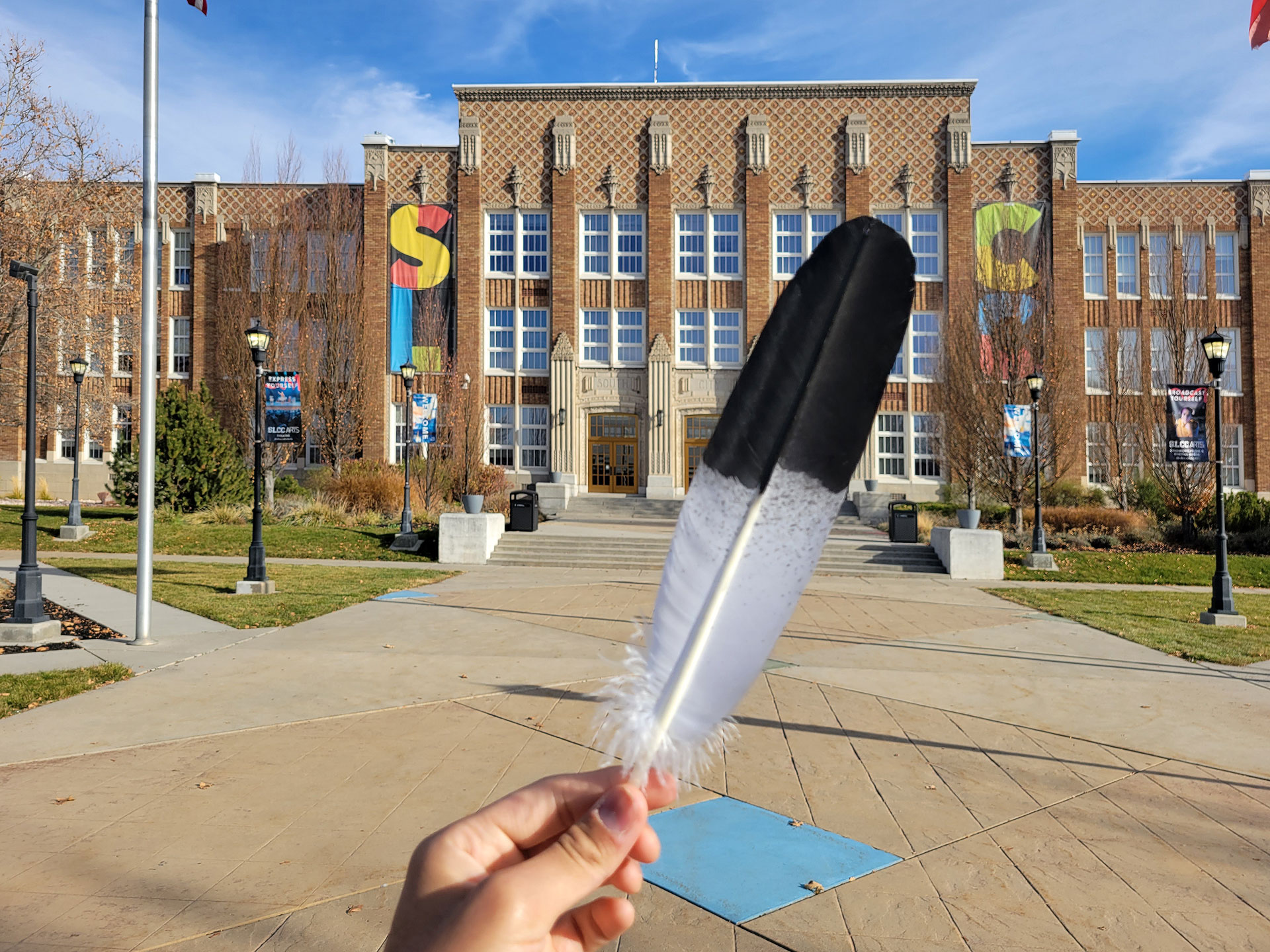 Person holding a feather in front of a brick building