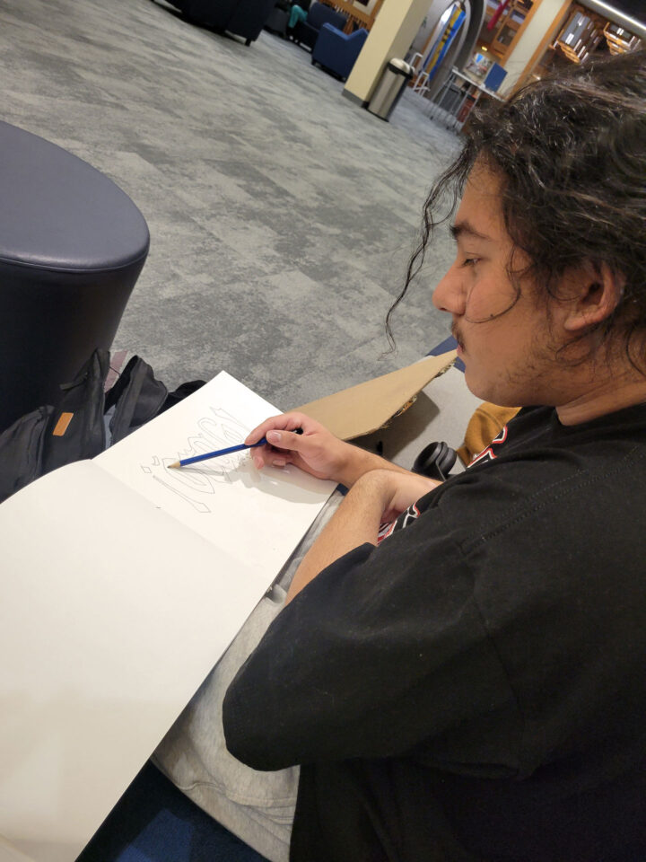 Nathanuel drawing in a sketchbook