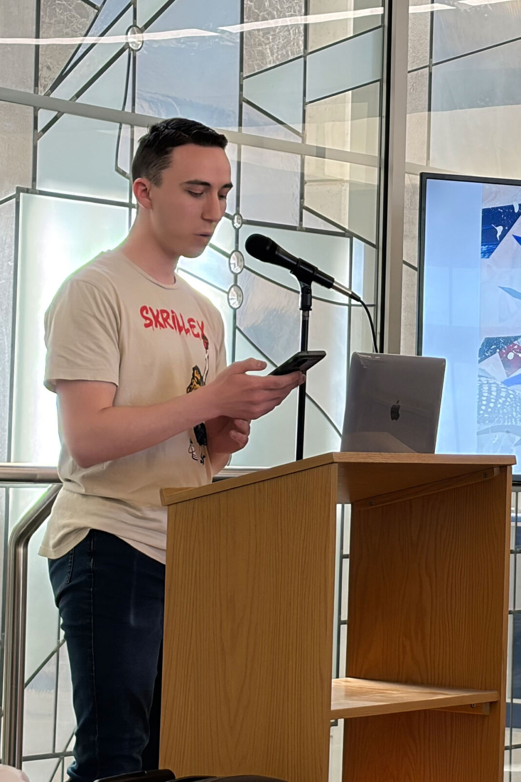 Young person reading from their phone while standing at a lectern