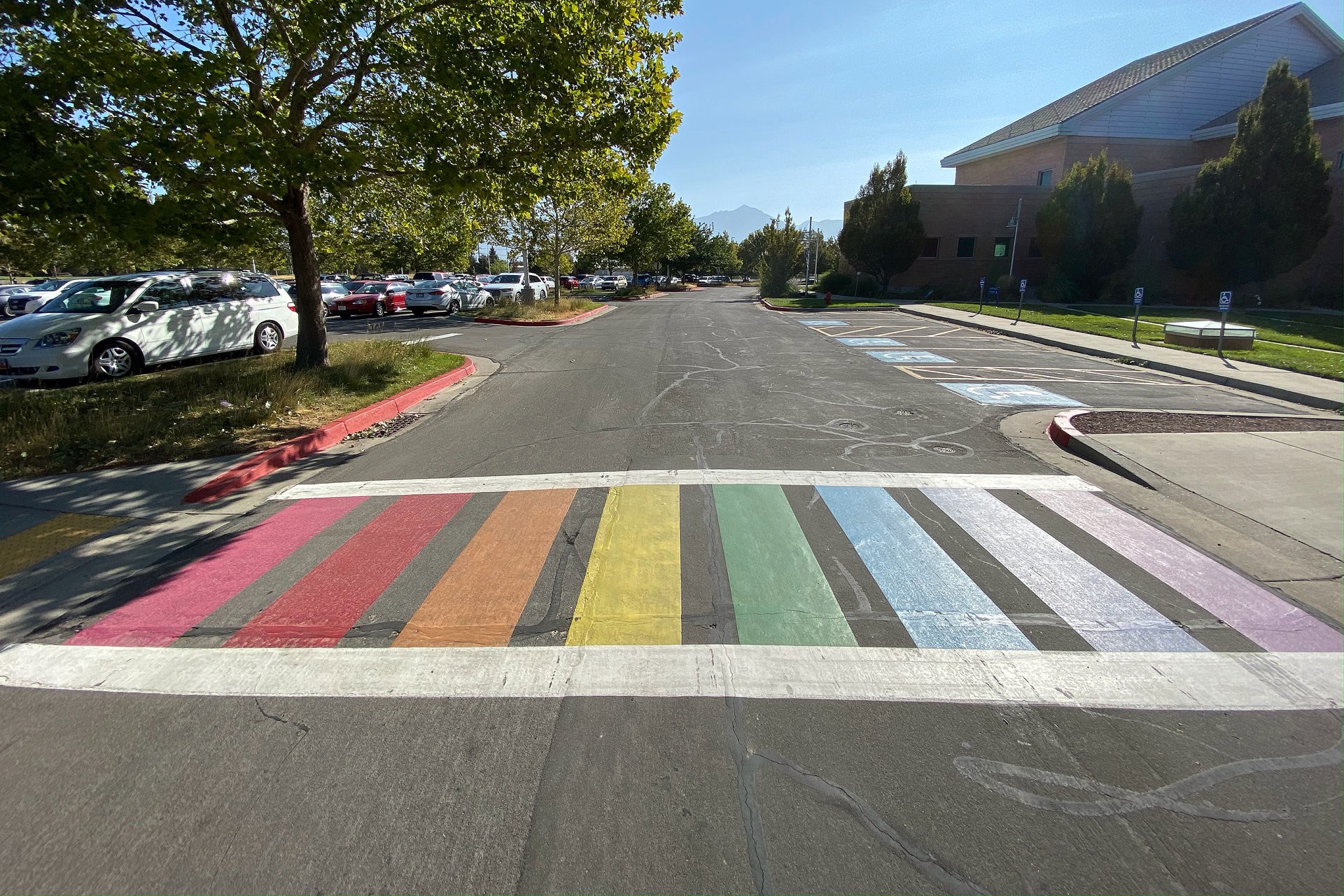 A ladder-style zebra crosswalk painted with rainbow colors