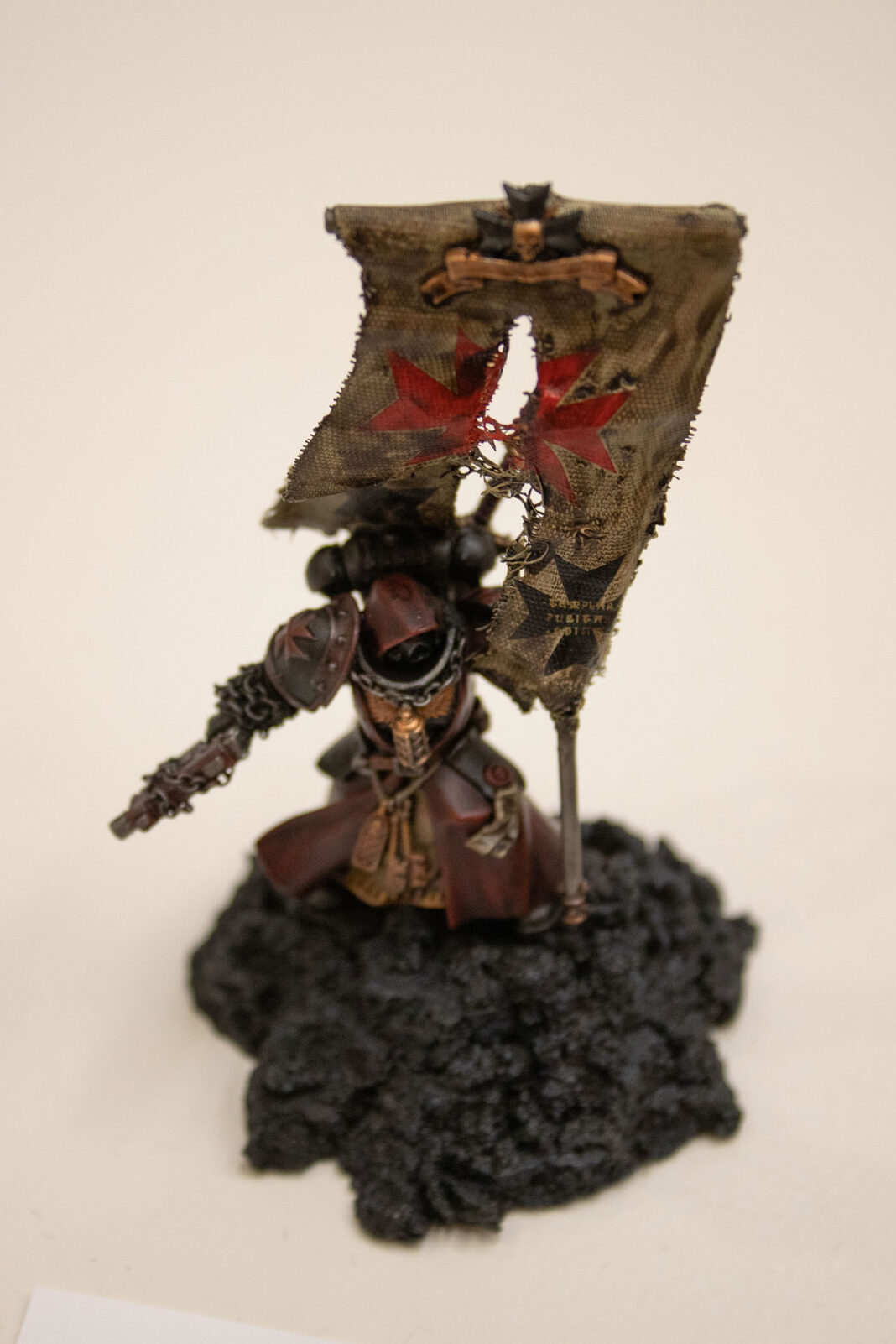 Sculpture of a knight standing on rock holding a torn flag with a Maltese cross