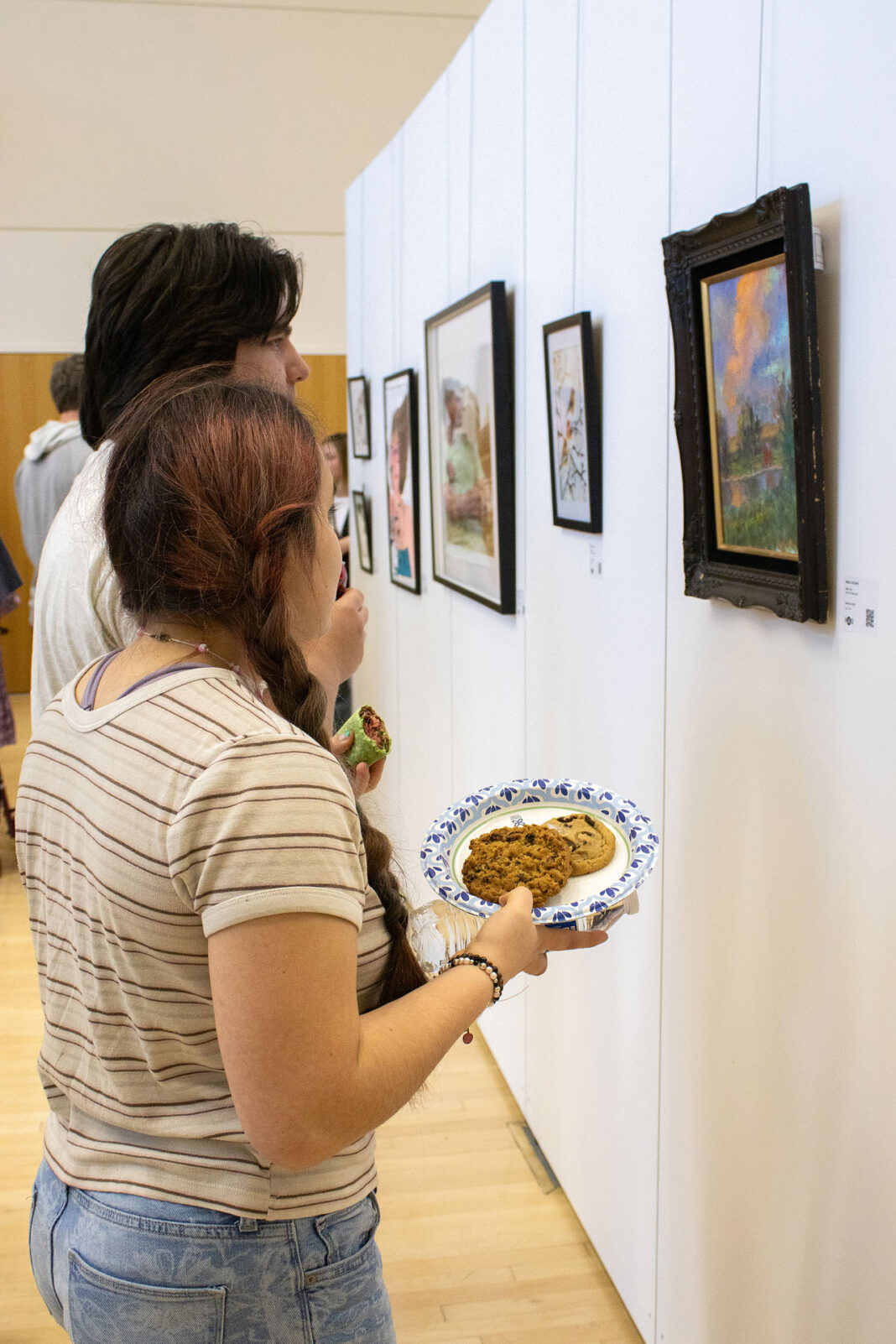 People viewing art while eating cookies in a gallery