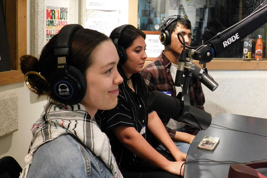Three students sitting at microphones during a radio show