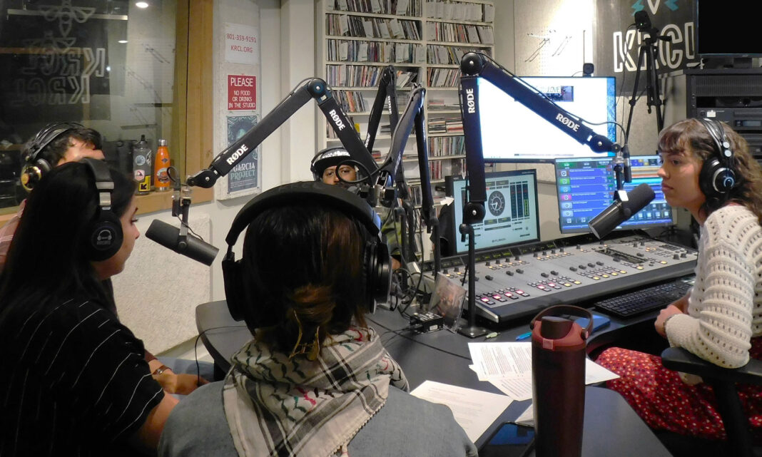People speaking into microphones inside a radio booth during a talk show