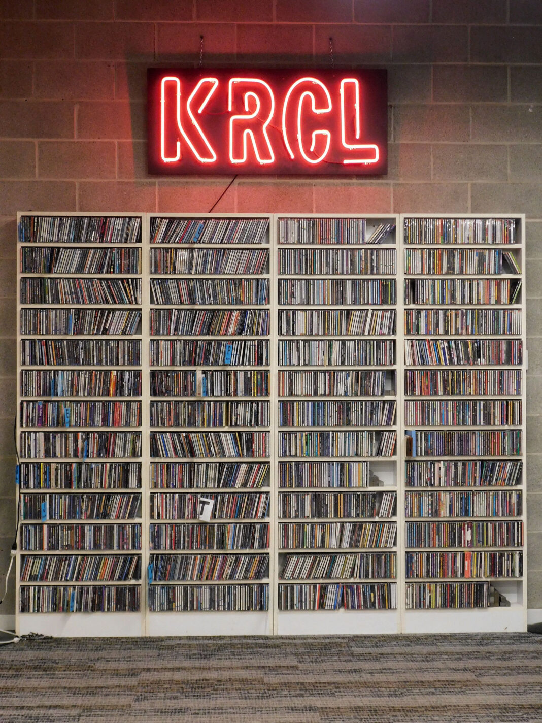 Lit KRCL sign mounted above shelves of CDs