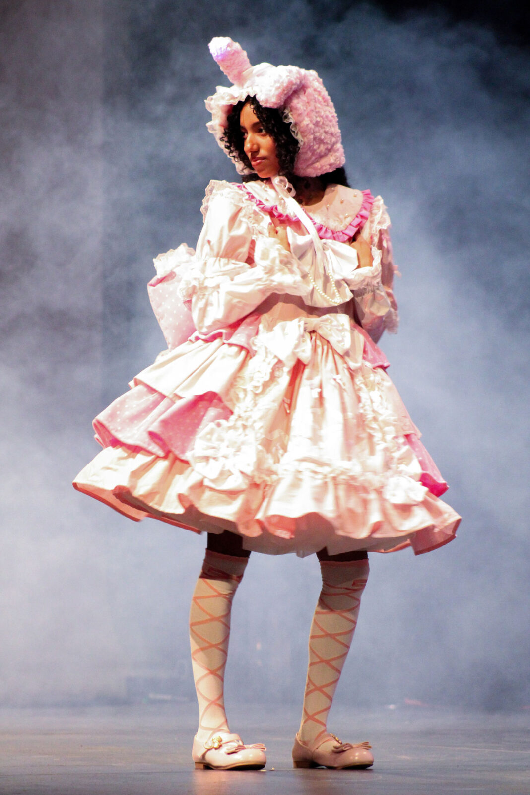 Model wearing a pink and white costume on a stage