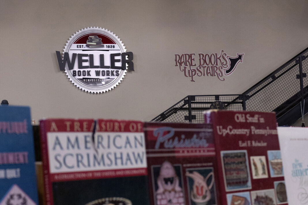 Books blurred in foreground with Weller Book Works logo and rare books upstairs on a wall