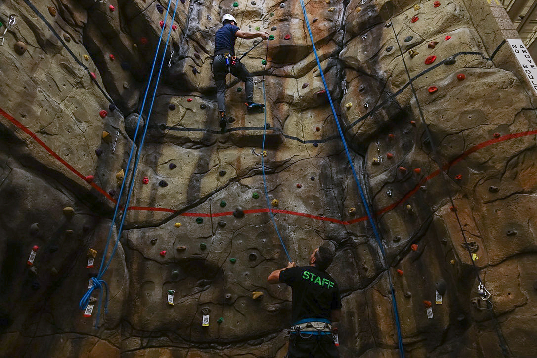 Climber ascending a rock wall with an instructor standing below