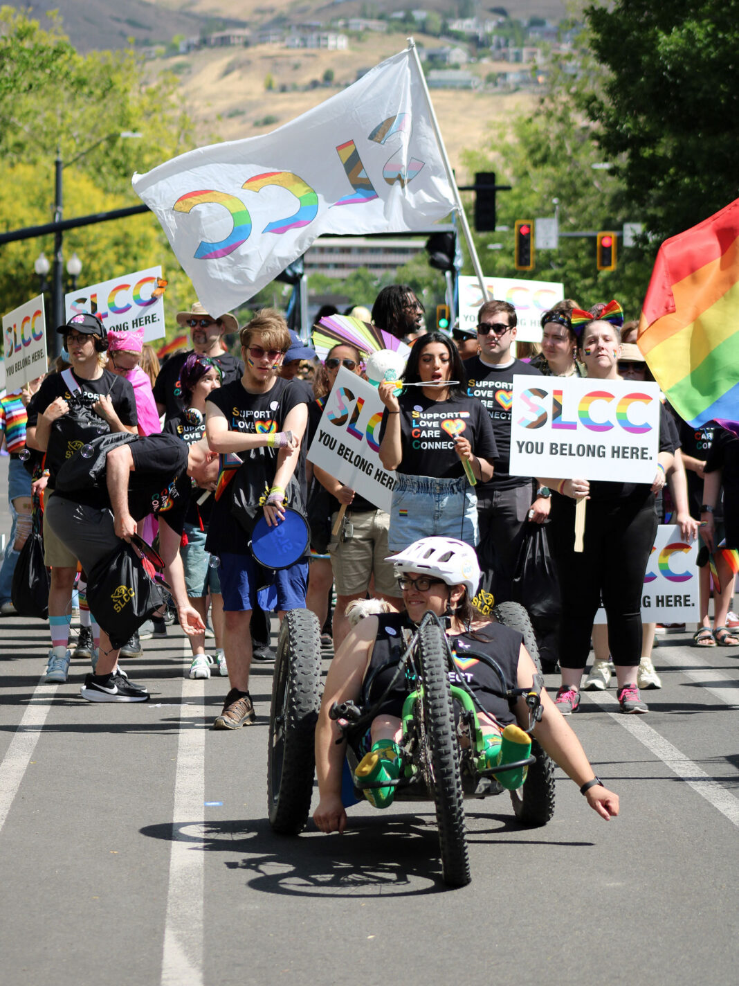A hand cyclist leading a group of parade walkers on a city street