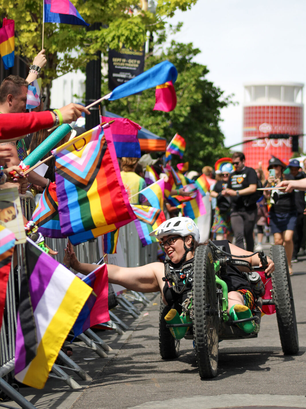 Hand cyclist interacting with Pride parade attendees on a city street