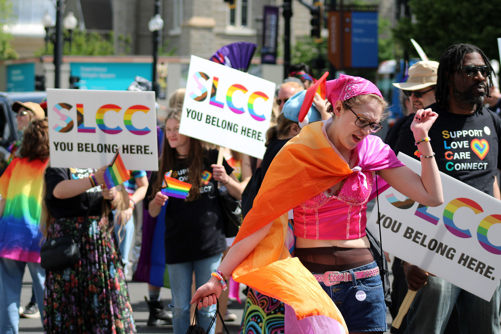 People holding SLCC signs behind a dancing paradegoer