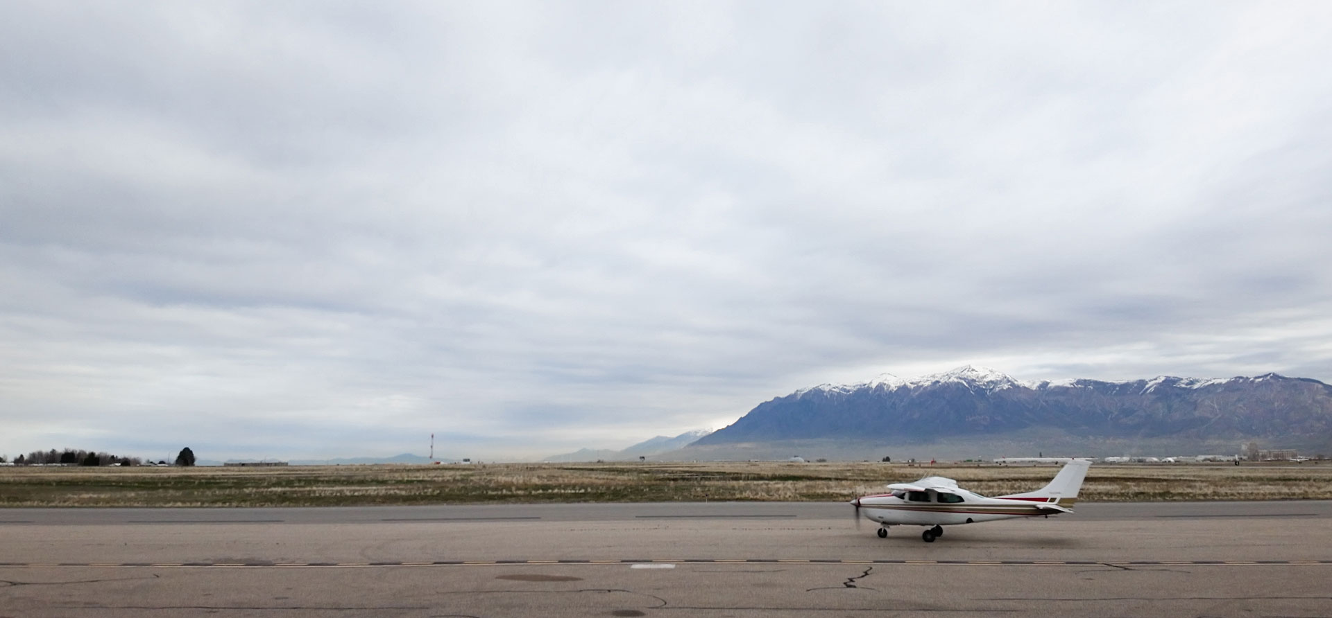 White plane with red and gold markings taxiing on a runway under a cloudy sky