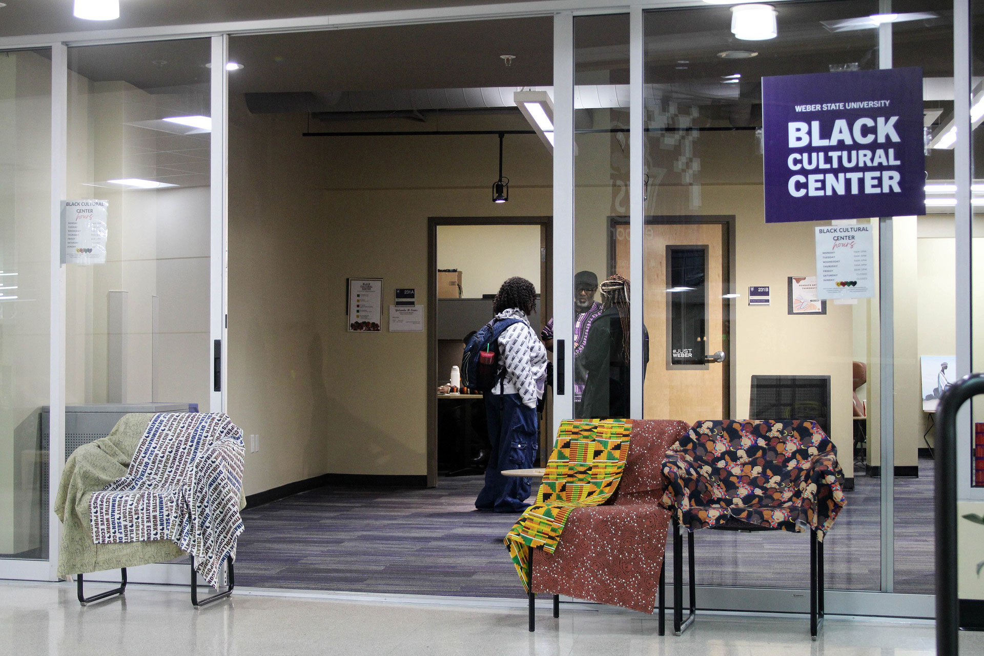 Multiple people standing and talking inside a lounge area with a Black Cultural Center sign near the entrance