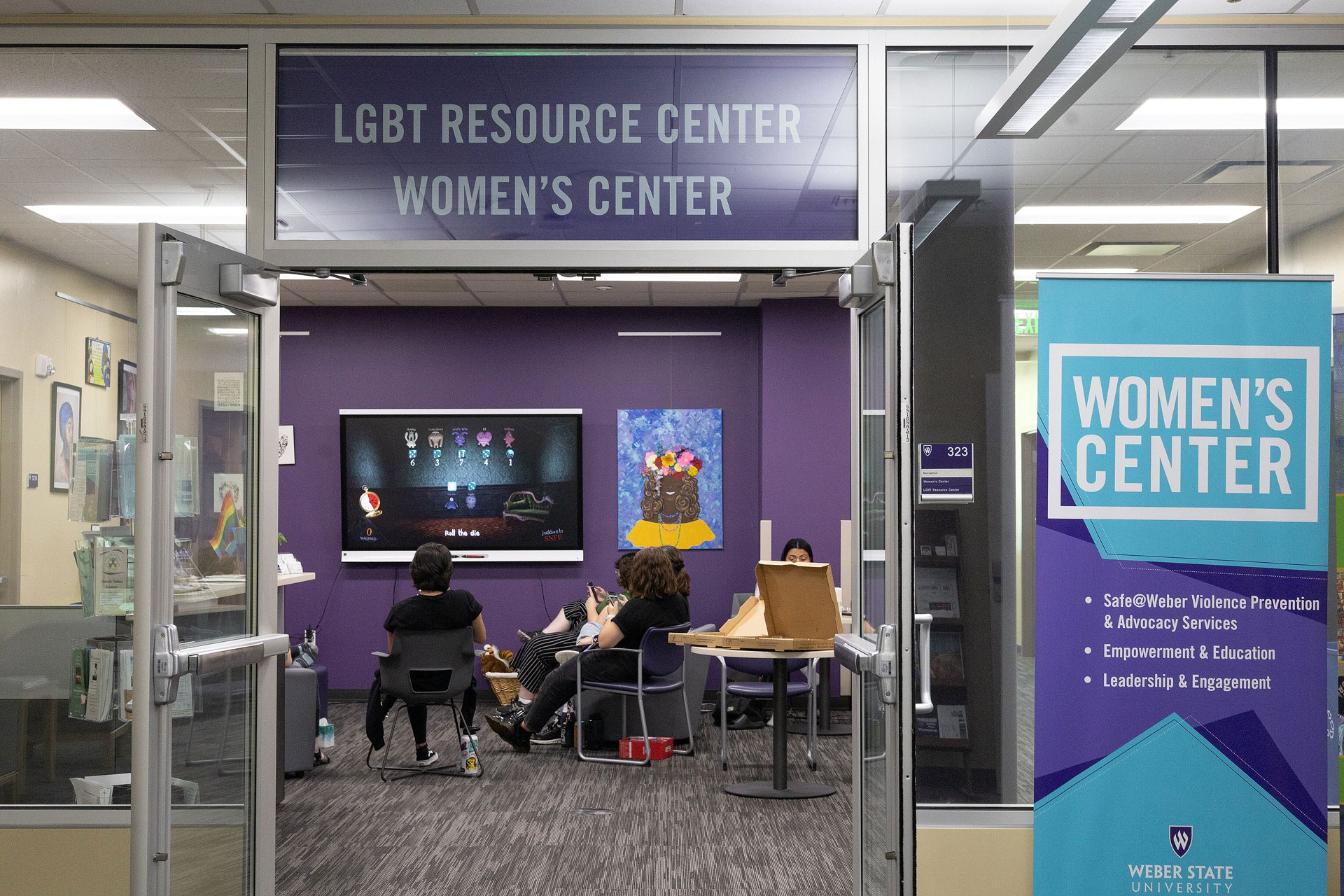 Several people sitting inside a lounge area with Women's Center signage outside the entrance