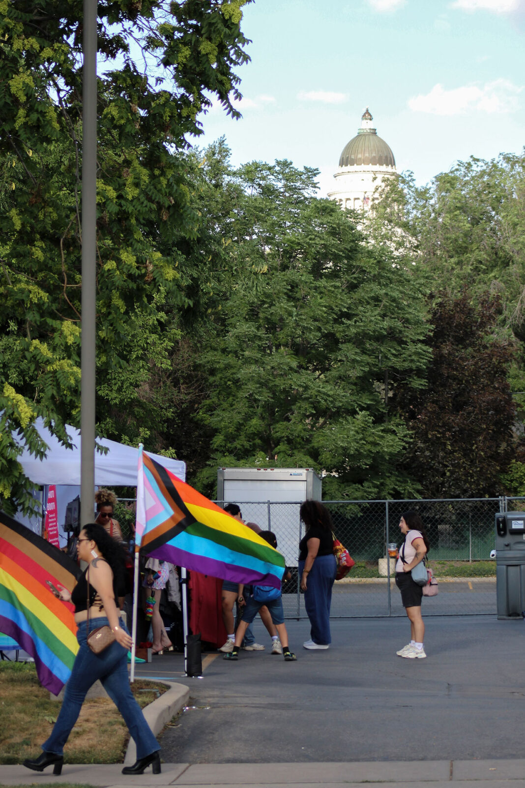 Festivalgoers visiting booths with the Utah State Capitol in the background behind trees