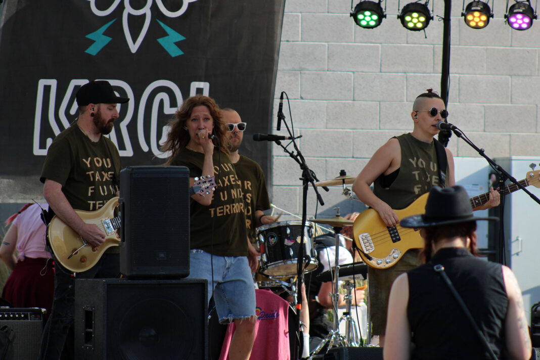Four members of a band performing on a stage during a festival